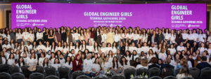 Large group gathered on stage at Global Engineer Girls Istanbul Gathering 2026, with event branding displayed on purple backdrop behind participants.